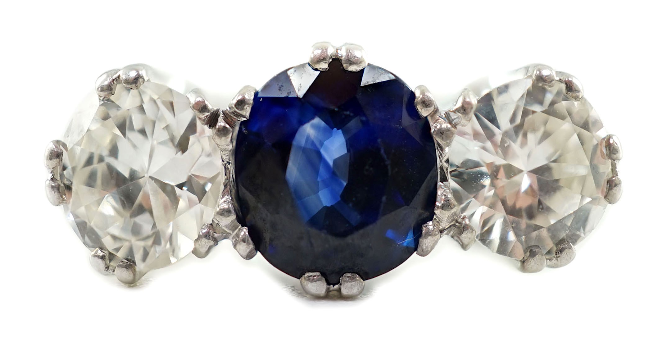 A modern 18ct white gold, single stone oval cut sapphire and two stone round cut diamond set ring